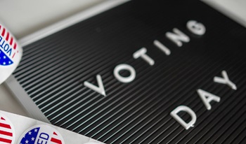 letterboard that says Voting Day next to a roll of American flag themed I Voted stickers