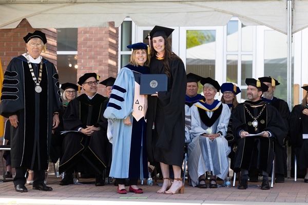 Chancellor Elliman, Dean Bradley and CoSPH diploma representative on stage in regalia