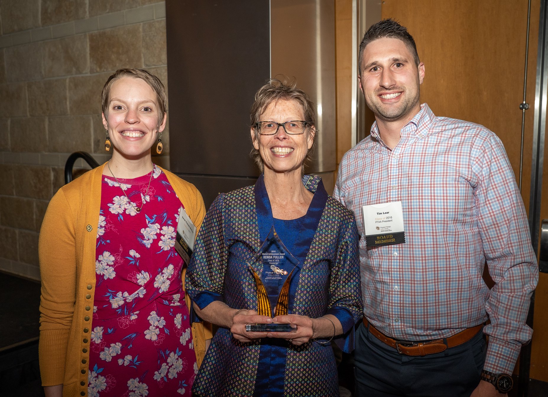 Kenda Fuller smiling as she accepts her 2019 Alumni Achievement Award from two department board members.