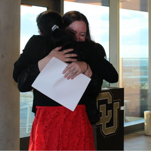 Two women embrace emotionally next to a CU podium during speeches at the Bardsley Foundation Awards celebration 2024