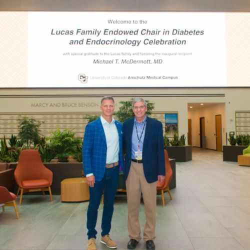 Benefactor and faculty stand in front of the jumbotron on the Health Sciences Building promoting the establishment of the new endowed chair.