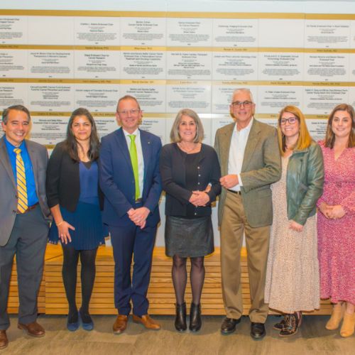 Benefactors pose with faculty in front of the Endowed Chairs Wall at the endowed chairs celebration.