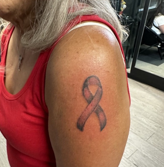 A woman poses to show here freshly inked breast cancer awareness ribbon tattoo on her left arm.