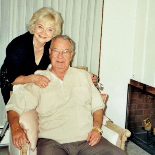 Jo Ann Bickham poses next to a fireplace with candles inside with her now deceased husband Clay.