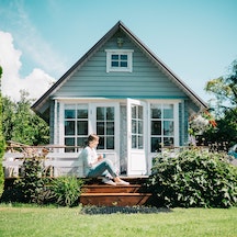 woman sitting on front porch of blue house
