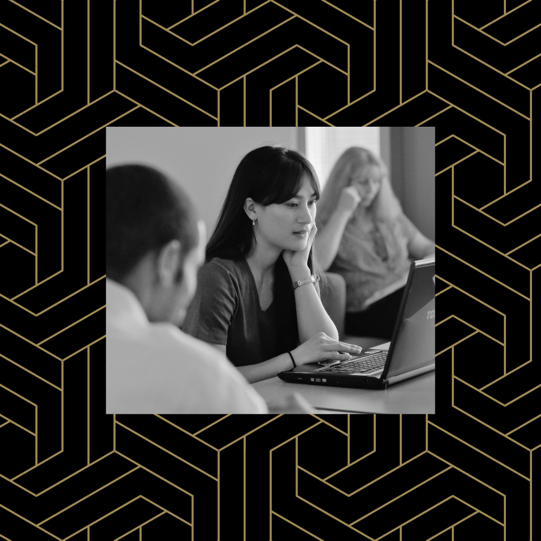 Black and white image of a student looking at a computer screen over a black and gold geometric background.