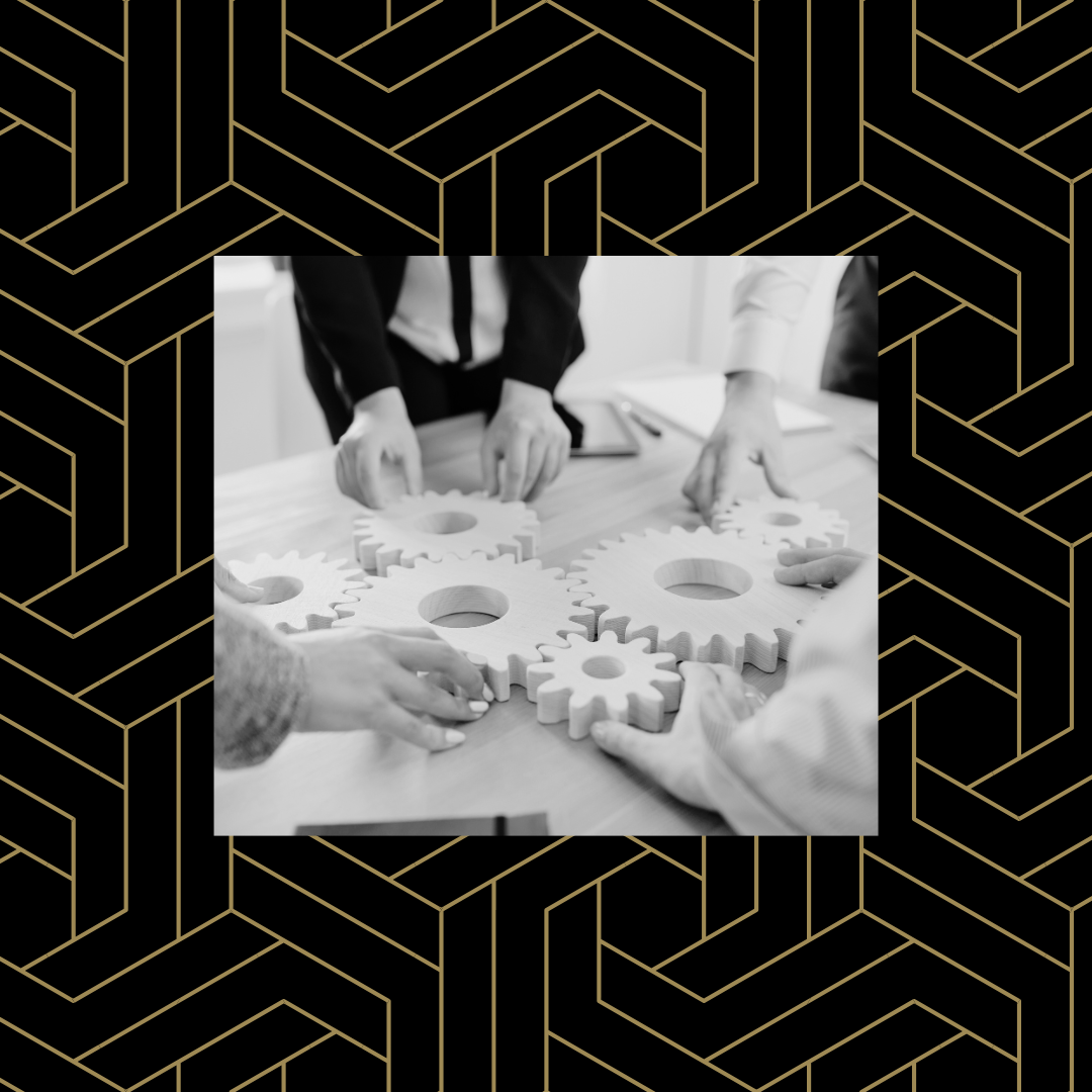 Black and white image of hands arranging cogs over a black and gold geometric background.
