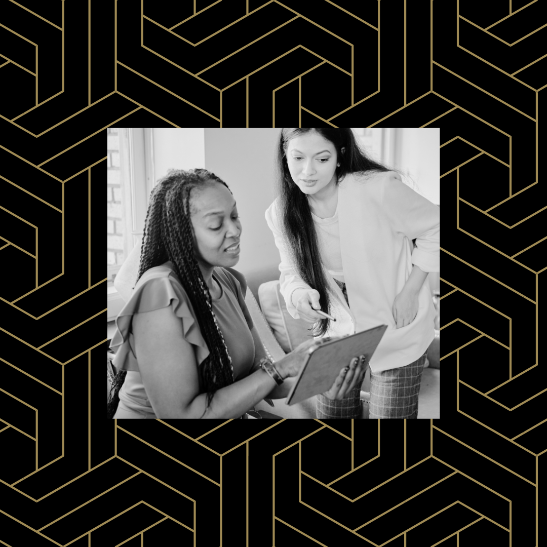 Black and white image of two individuals speaking while looking at a tablet over a black and gold geometric background.