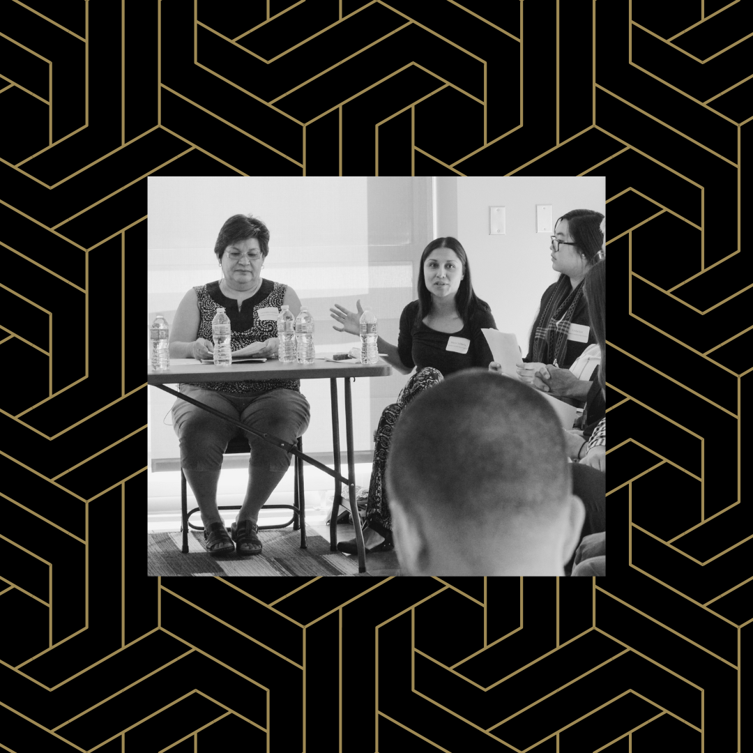 Black and white image of three at a table talking over a black and gold geometric background.