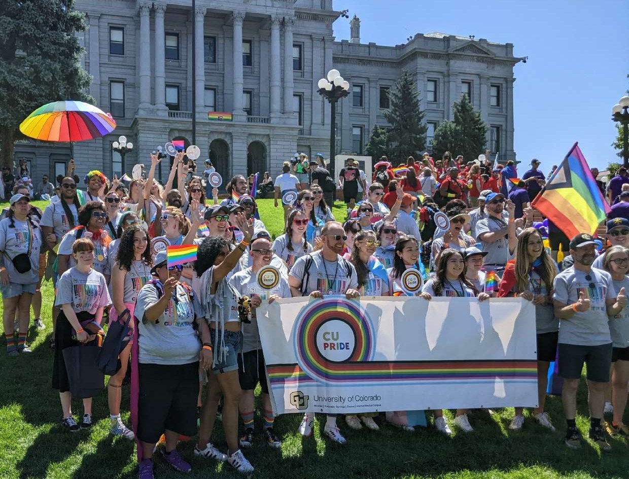 A large group of CU students, staff, and faculty stand for a group photo outside of the Colorado Capital building during 2023 Pride activities