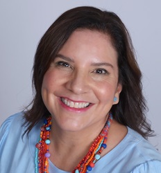 Professional headshot of Patricia Alvarez Valverde; she smiles and wears a light blue top with a bright, colorful necklace.