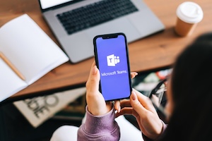 Adobe stock pic of a person holding a cell phone in their hand showing the Microsoft Teams image