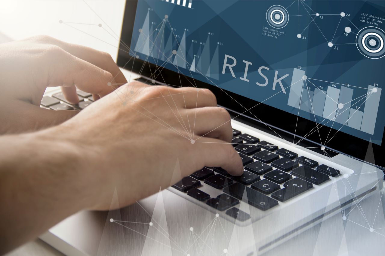 AdobeStock_109035238 Website Image of hands on a keyboard while the screen shows data points and the word RISK.